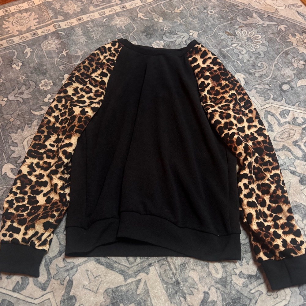 Stylish black top with eye-catching leopard print sleeves. Perfect for adding a